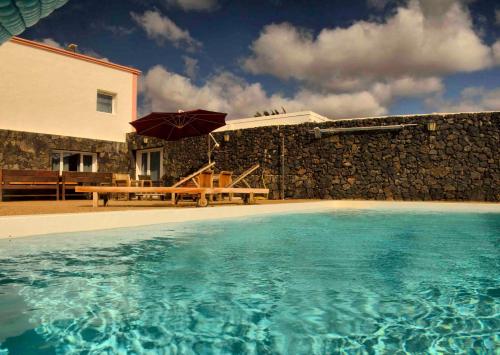 a house with a pool and a table and an umbrella at Casa Juanita in Puerto Calero