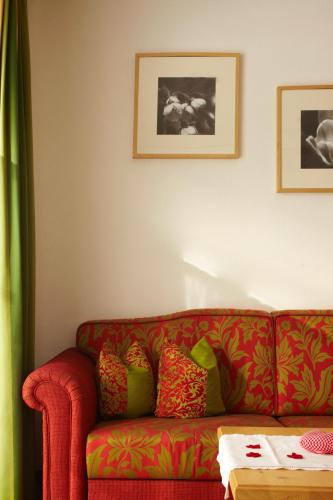 a red couch with colorful pillows in a living room at Landhaus Alpensonne in Schattwald