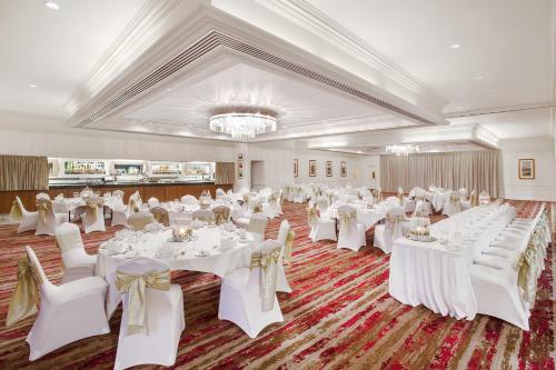 a banquet hall with white tables and chairs and a chandelier at Leonardo Hotel and Conference Venue Aberdeen Airport in Dyce