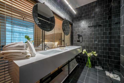 a bathroom with a white sink and black tiles at Artagonist Art Hotel in Vilnius