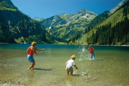 three people playing in the water at a lake at Landhaus Alpensonne in Schattwald