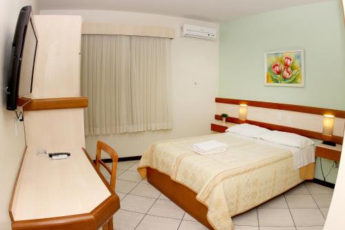 a hotel room with a bed and a refrigerator at Hotel Veneza in Brusque