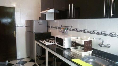 a kitchen with a sink and a microwave at Addoha Apartment in Tangier