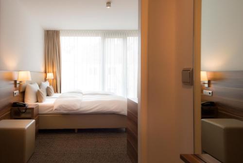 a hotel room with a bed and a window at Downtown Vi Vadi Hotel in Munich