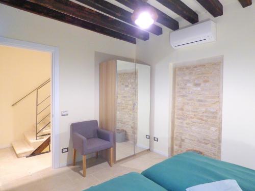 a bedroom with a blue chair and a mirror at Ca' Neldo - VeniseJeTAime in Venice