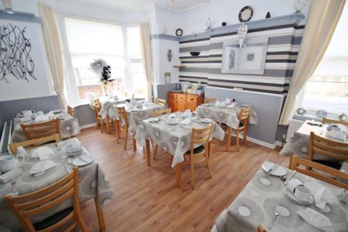 a dining room with white tables and chairs at Serena Court Hotel in Skegness