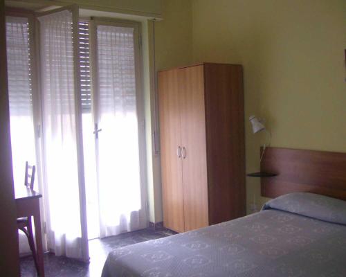 a bedroom with a bed and a wooden cabinet at Pensione Aurora in Imperia