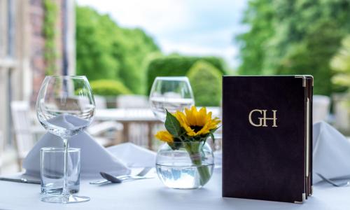 a table with two wine glasses and a book at Goldsborough Hall in Knaresborough