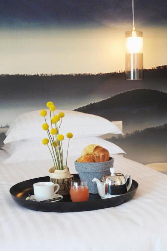 a plate of food with bread and coffee on a bed at L’Échappée Belle in LʼIsle-Jourdain