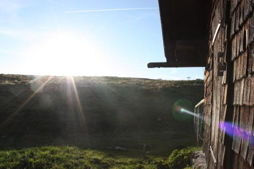 a building with the sun shining in a field at Das Prinzis in Lofer