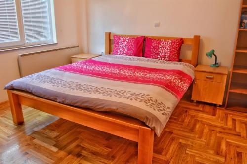 a bed with red and pink pillows in a bedroom at Apartments Elena in Ohrid