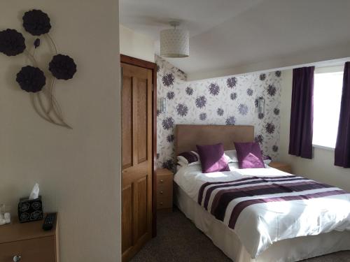 a bedroom with a bed with purple pillows and a window at Camelot House in Blackpool