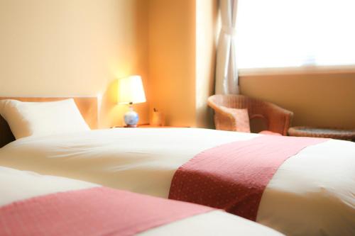 a hotel room with two beds and a window at 旅館かわな -Ryokan Kawana- in Kimitsu