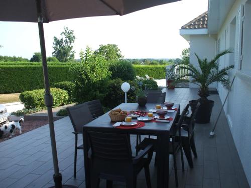une table avec des chaises et un parasol sur une terrasse dans l'établissement Les Varennes, à Saint-Alban-les-Eaux