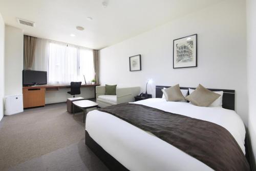 a hotel room with a large bed and a desk at Hotel Tohkai in Atsugi