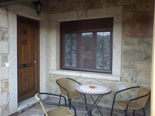 a table and chairs on a porch with a window at El Cerrillo II in San Martín del Pimpollar