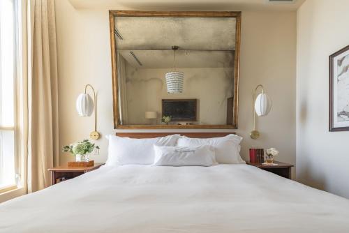 a bedroom with a large white bed and a mirror at The Dewberry Charleston in Charleston