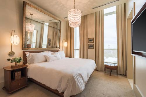 a bedroom with a large white bed and a mirror at The Dewberry Charleston in Charleston