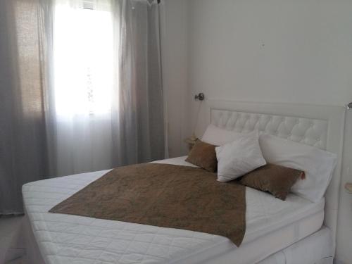 a bedroom with a white bed with pillows and a window at Habana Beach Flat in Natal