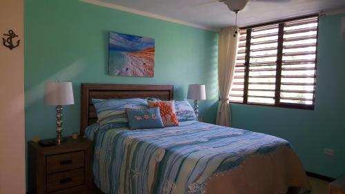 Dormitorio azul con cama y ventana en Fully Air-Conditioned Beach Front Penthouse Apartment en Naguabo