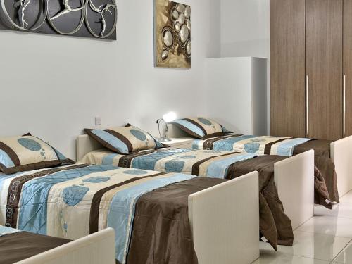 a group of four beds in a room at Water's Edge Apartment in St. Paul's Bay