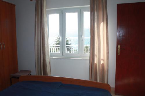a bedroom with a window with a view of the ocean at Apartman Anka in Viganj