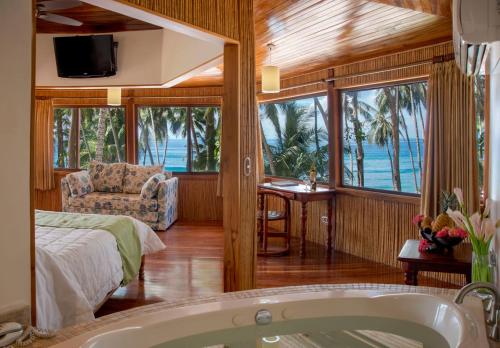 a bedroom with a bed and a tub in a room at Tango Mar Beachfront Boutique Hotel & Villas in Tambor