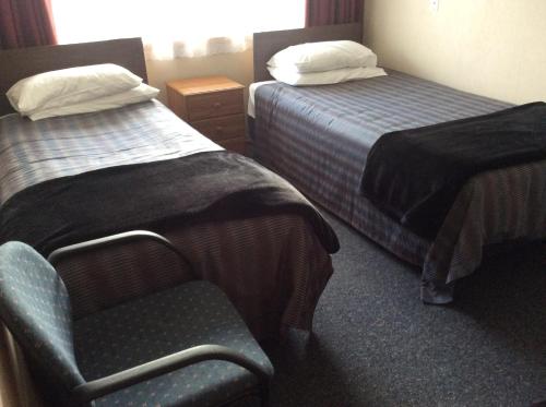 a hotel room with two beds and a chair at Charlton Motel in Gore