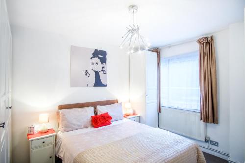 Schlafzimmer mit einem Bett mit roten Kissen und einem Fenster in der Unterkunft Quality Stylish Flat in Russell Square in London