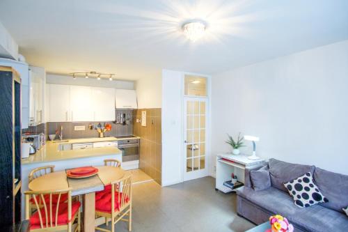 eine Küche und ein Wohnzimmer mit einem Sofa und einem Tisch in der Unterkunft Quality Stylish Flat in Russell Square in London