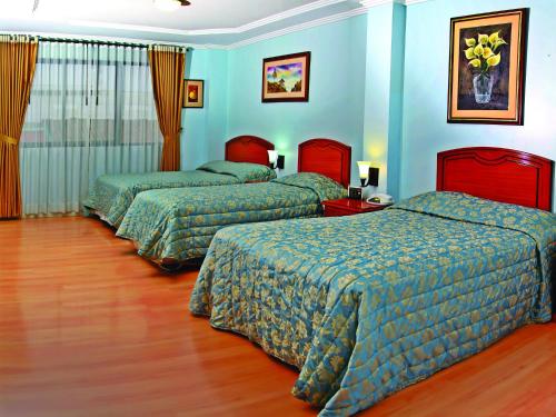 two beds in a hotel room with blue walls at Hotel Yanuncay in Cuenca