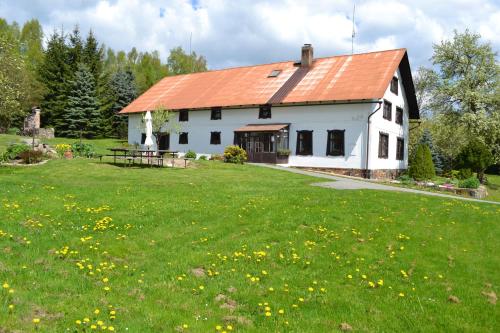 a white house with an orange roof in a field of grass at Chalupa pod Klepáčem in Králíky