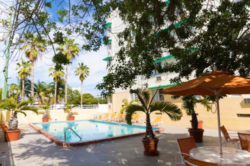 a swimming pool with tables and chairs and an umbrella at Broadmore Miami Beach in Miami Beach