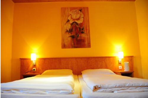 two beds in a bedroom with two lights on them at Hotel Schäferhof in Bückeburg