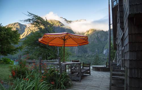 a table with an umbrella on a wooden deck at Barraco Lodge in Puelo