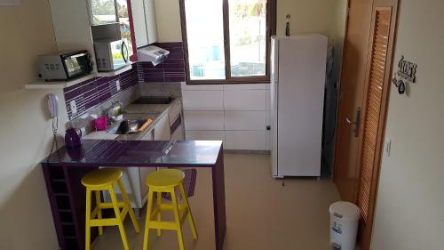 嘎林海斯港的住宿－Oka Beach Residence，厨房在柜台上设有两个黄色凳子