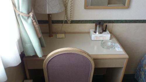 a table with a blender and a chair in a room at Business Hotel Motonakano in Tomakomai