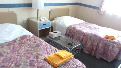 a hotel room with two beds and a table at Business Hotel Motonakano in Tomakomai
