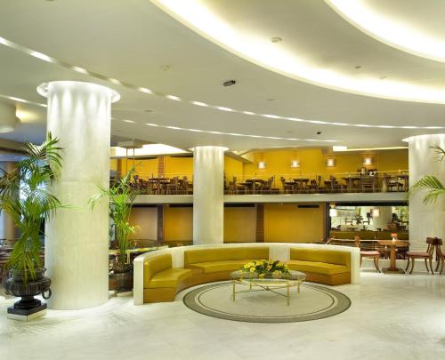 a hotel lobby with a yellow couch and a table at Titania Hotel in Athens