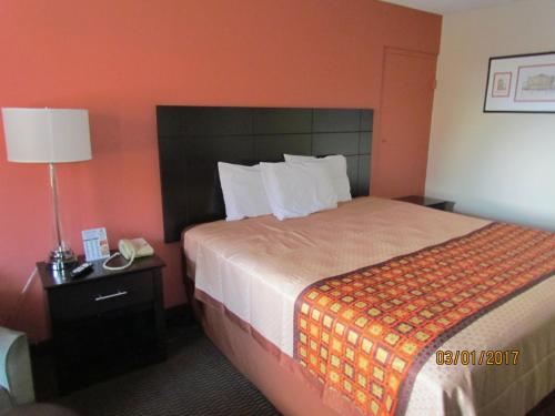 a hotel room with a bed and a lamp at Travelers Lodge Beatrice in Beatrice