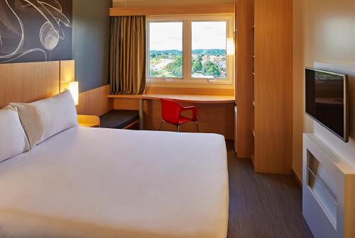 a room with a bed and a desk and a window at ibis Rio Branco in Rio Branco