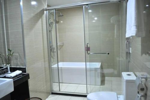 a bathroom with a shower with a tub and a toilet at Ramada Linyi North in Linyi