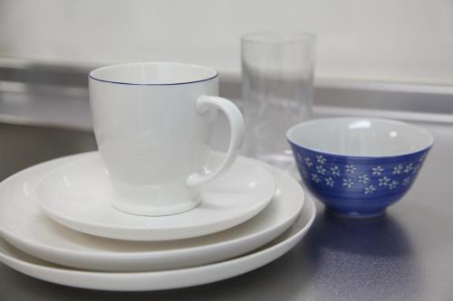 a white coffee cup and saucers on a table at Apartment Heights HANA in Sakai