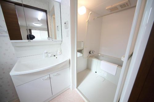 a white bathroom with a sink and a mirror at Apartment Heights HANA in Sakai