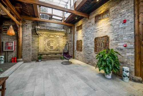 a room with a brick wall with a chair and a plant at Water Hotel, Pingyao in Pingyao