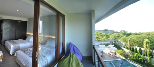 a balcony with a view of a bedroom and a pool at Padang-Padang Inn in Uluwatu