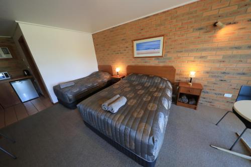a bedroom with a large bed and a leather couch at Quays Motel San Remo in San Remo