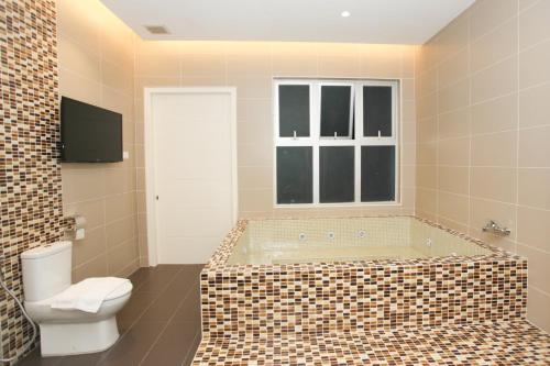 a bathroom with a bath tub and a toilet at Casa Bianca in Kluang
