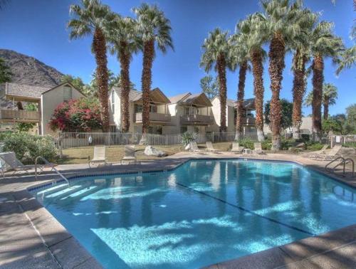 a large swimming pool with palm trees in a yard at Mountain Cove Private Condo in Indian Wells