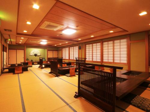 a large room with tables and chairs and windows at Yunohirakan in Takayama